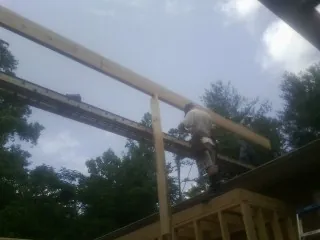 Carpenter setting a ridge beam over a new addition frame — Ice Dam Removal by Roofing Brothers in Elma