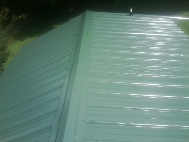 New green metal panels meeting at the ridge of a roof — Flat Roof Repair work by our crew in Elma