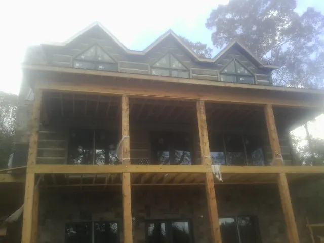 Dormers and porch framing on a large log home under construction — Roof Coating work by our crew in Elma