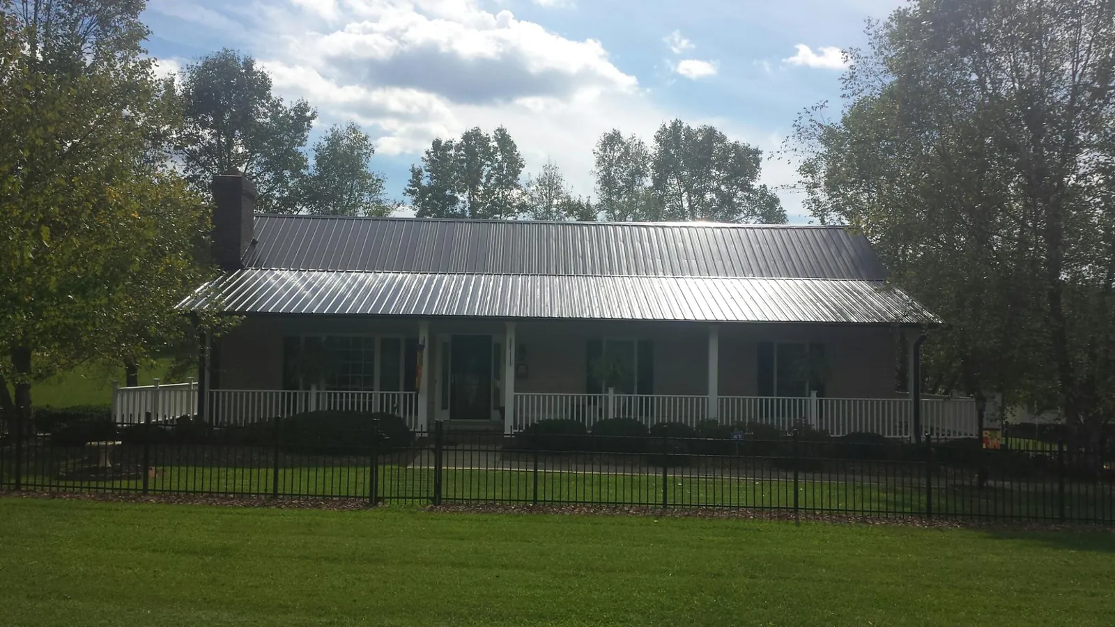 Gray metal roof on a brick ranch with a full width front porch — Gutter Guard Installation work by our crew in Elma