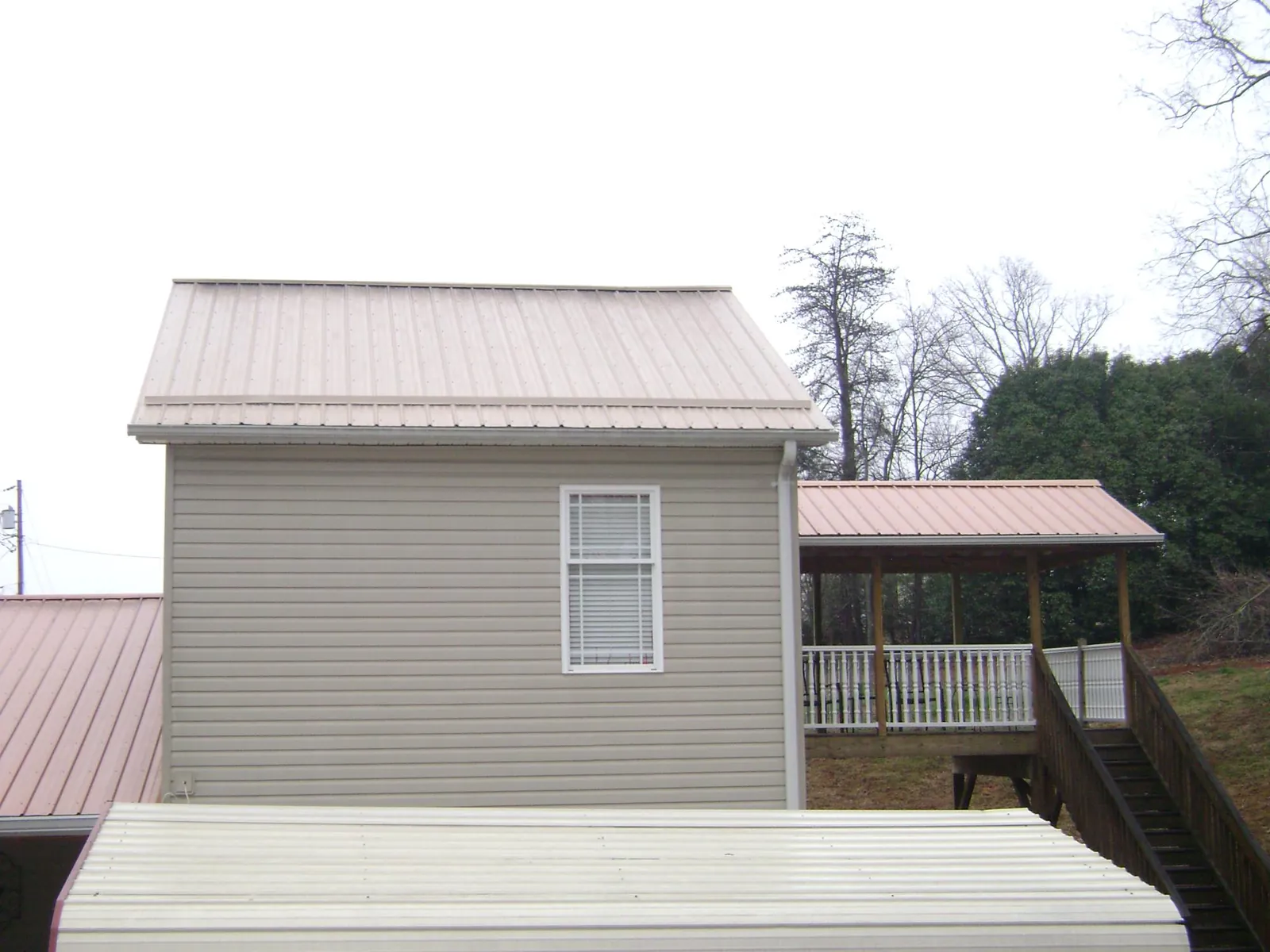 Tan metal roofs on a two story addition and attached porch in Elma